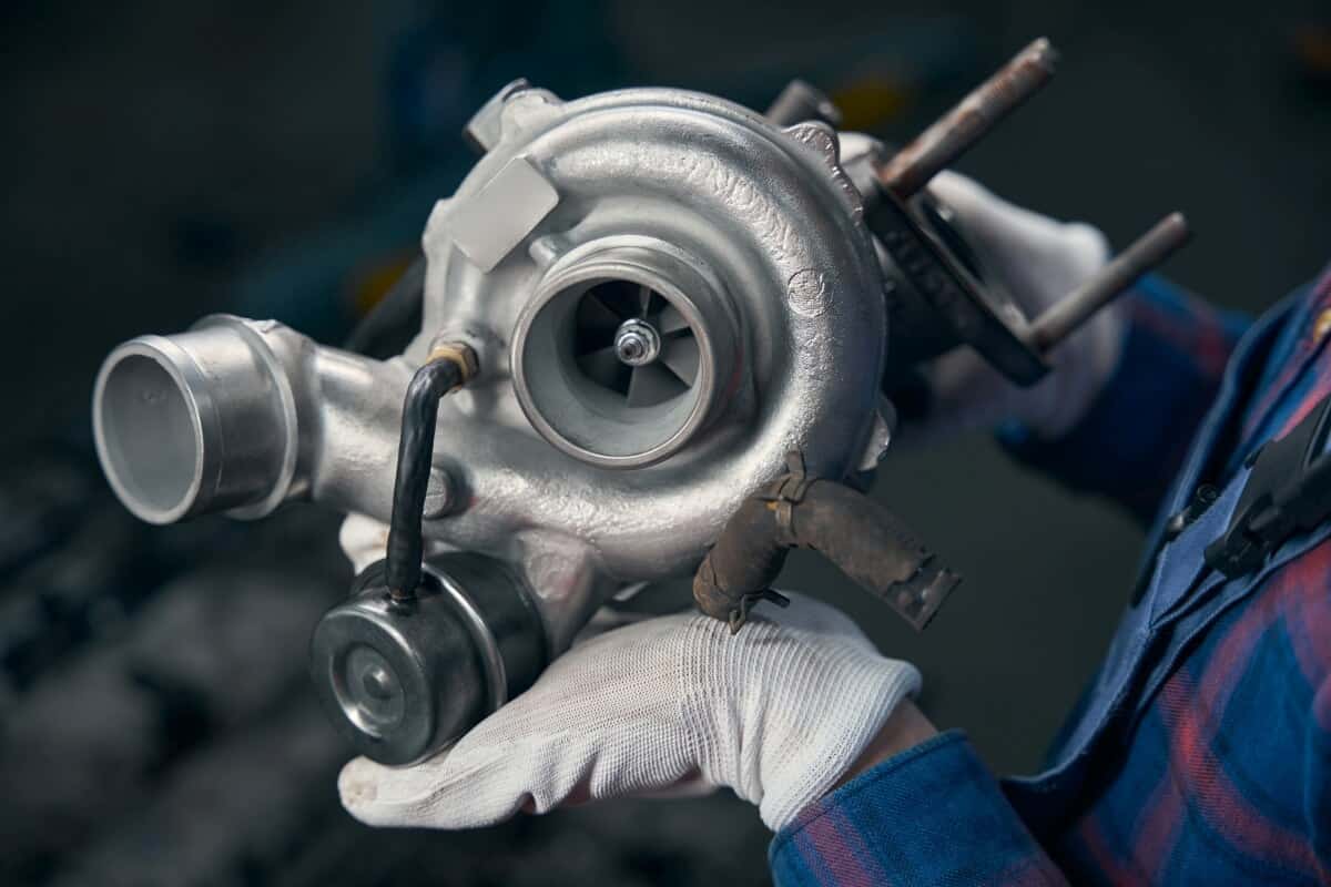 Mechanik trzyma w rękach turbosprężarkę po regeneracji.