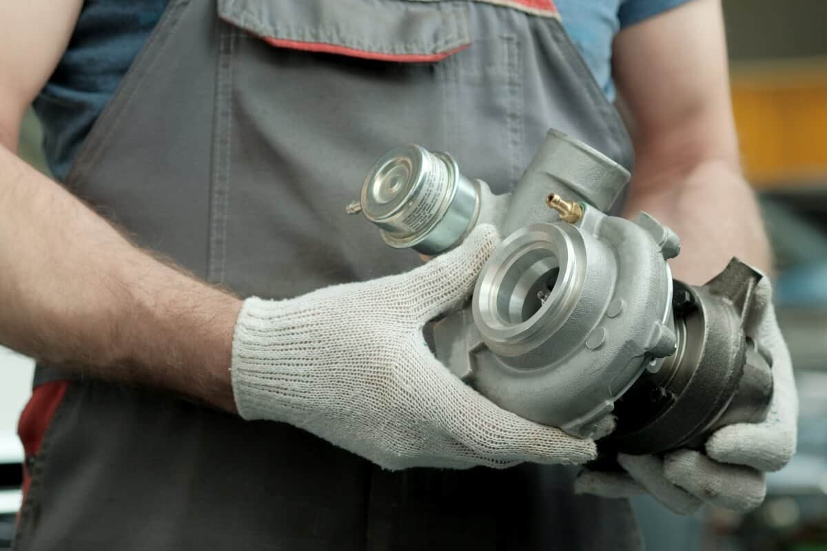 Mechanik trzyma turbosprężarkę przygotowaną do regeneracji turbosprężarki.