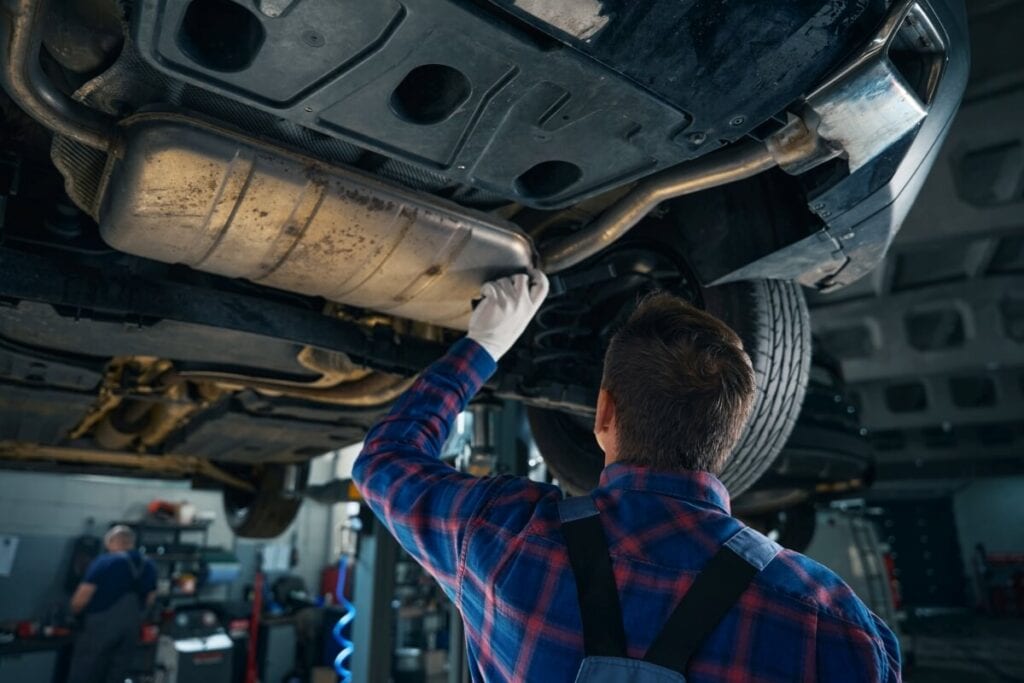 Mechanik przeprowadza regenerację katalizatora SCR pod podniesionym samochodem.