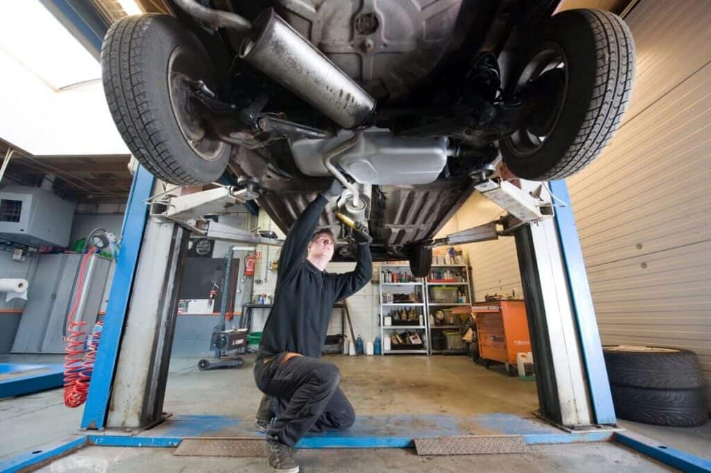 Mechanik pracuje pod samochodem, przeprowadzając regenerację katalizatora SCR.