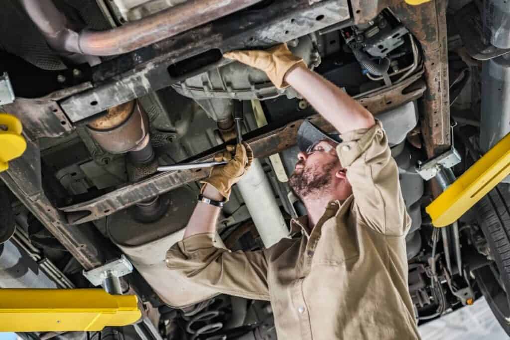 Mechanik pracuje pod samochodem, przeprowadzając czyszczenie filtra DPF.