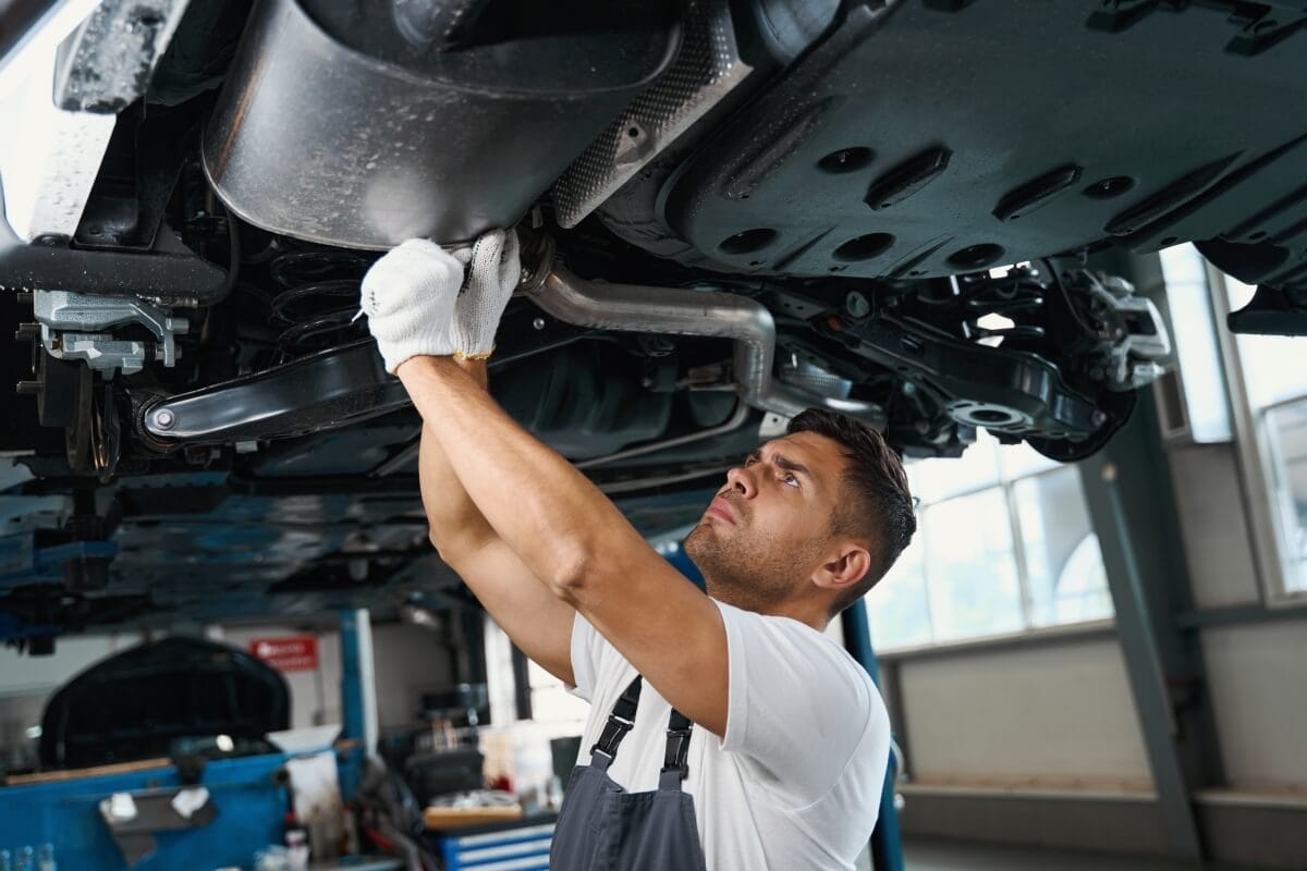 Mechanik pracuje pod samochodem, gdzie wykonuje regenerację katalizatora SCR.