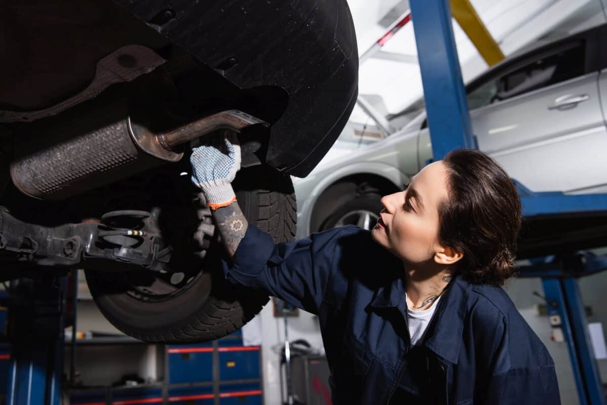 Mechaniczka sprawdza układ wydechowy auta na podnośniku w związku z czyszczeniem filtra DPF