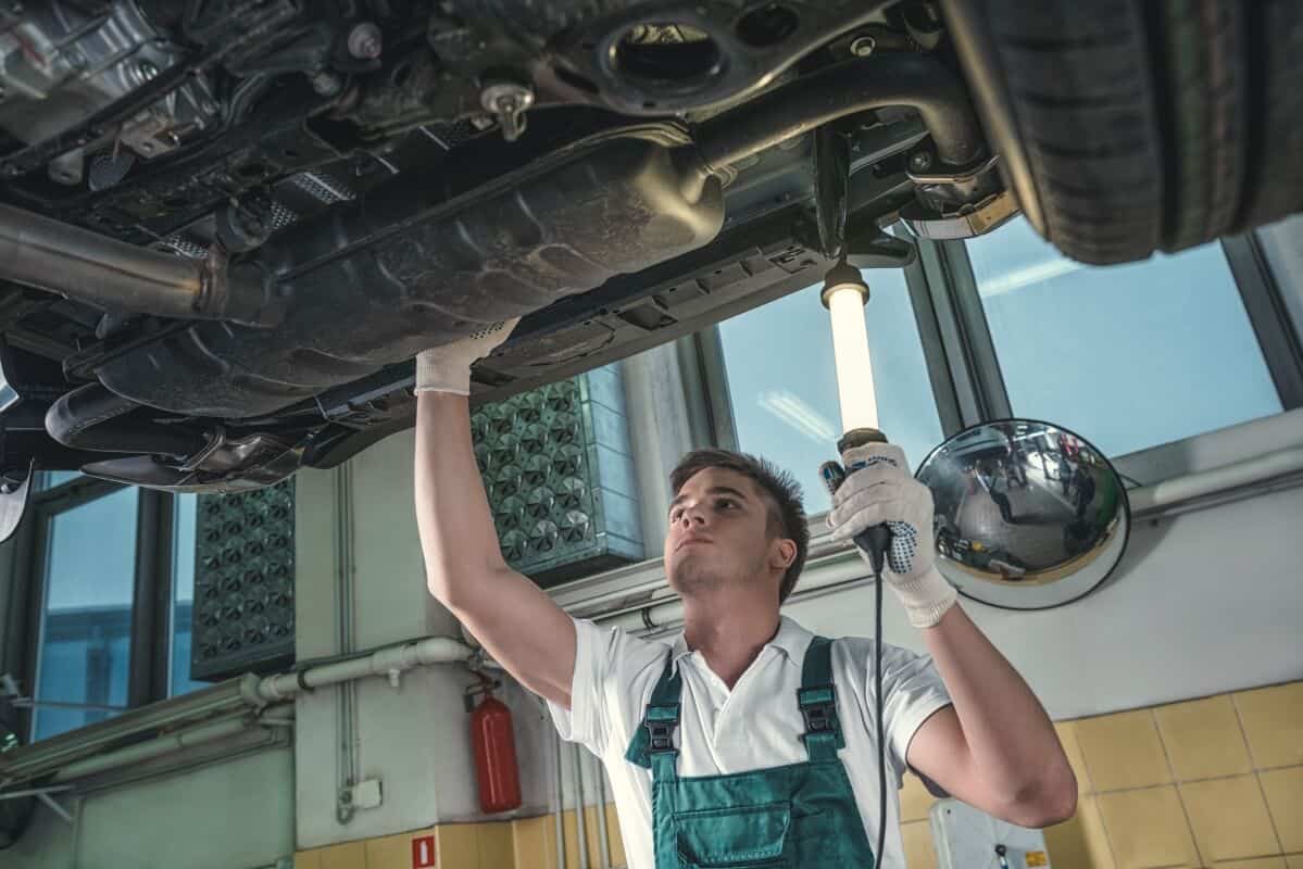Mechanik pod uniesionym samochodem kontroluje podwozie w związku z regeneracją katalizatora SCR