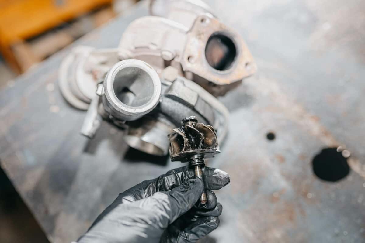 Mechanik trzyma wirnik turbosprężarki podczas oceny, czy regeneracja turbosprężarki jest możliwa po chip tuningu